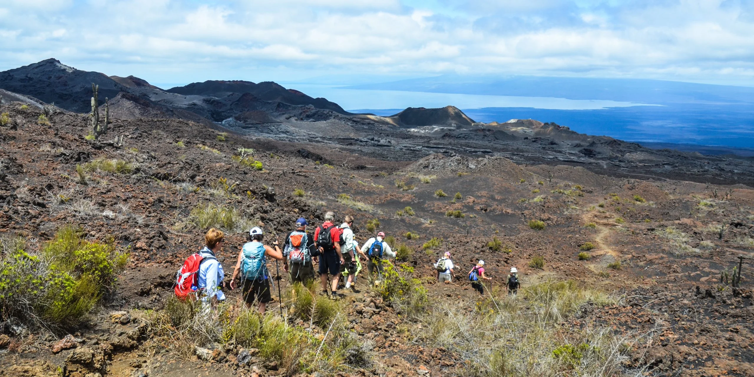 Travelers hiking volcanic terrain in Isabela Island