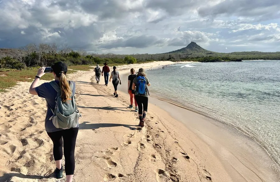 Travelers walking along a white-sand beach in the Galapagos